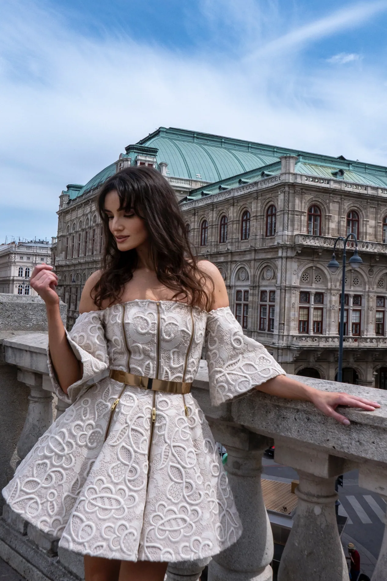 Model in a cream jacquard mini dress on a balcony in front of the Vienna State Opera
